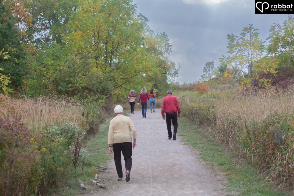 The backs of people walking on a trail with dark storm clouds.