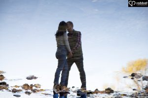 Reflection in water of a couple holding hands and touching heads at James Gardens.