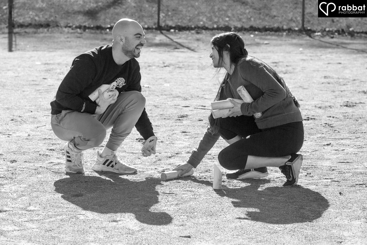 Couple looking into each other's eyes and smiling in a black and white photo in a baseball diamond as they pick up Molki sticks.
